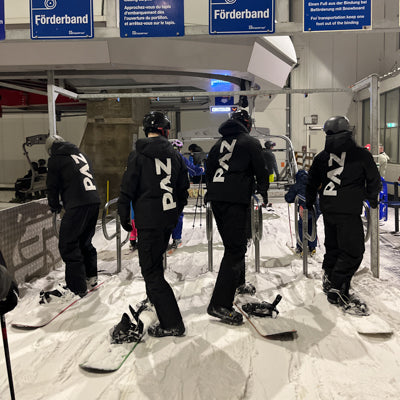 Snowboarder in PAZ Schneeanzügen warten am Skilift in der Skihalle